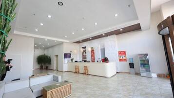 Vestíbulo de hotel con una recepción, zona de estar y una planta.