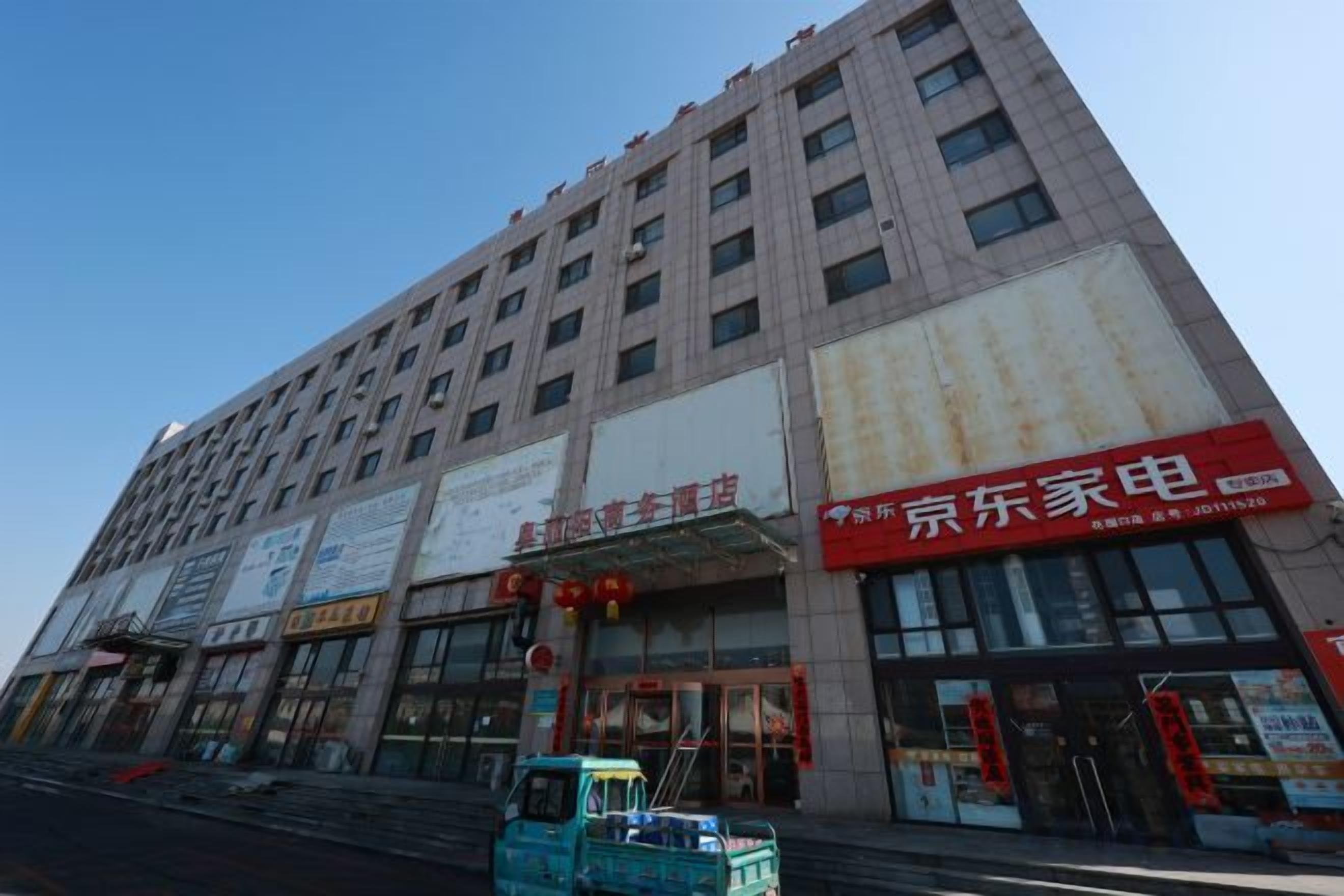 Un edificio de varios pisos con locales comerciales en la planta baja, incluyendo un restaurante visible con señalización roja.