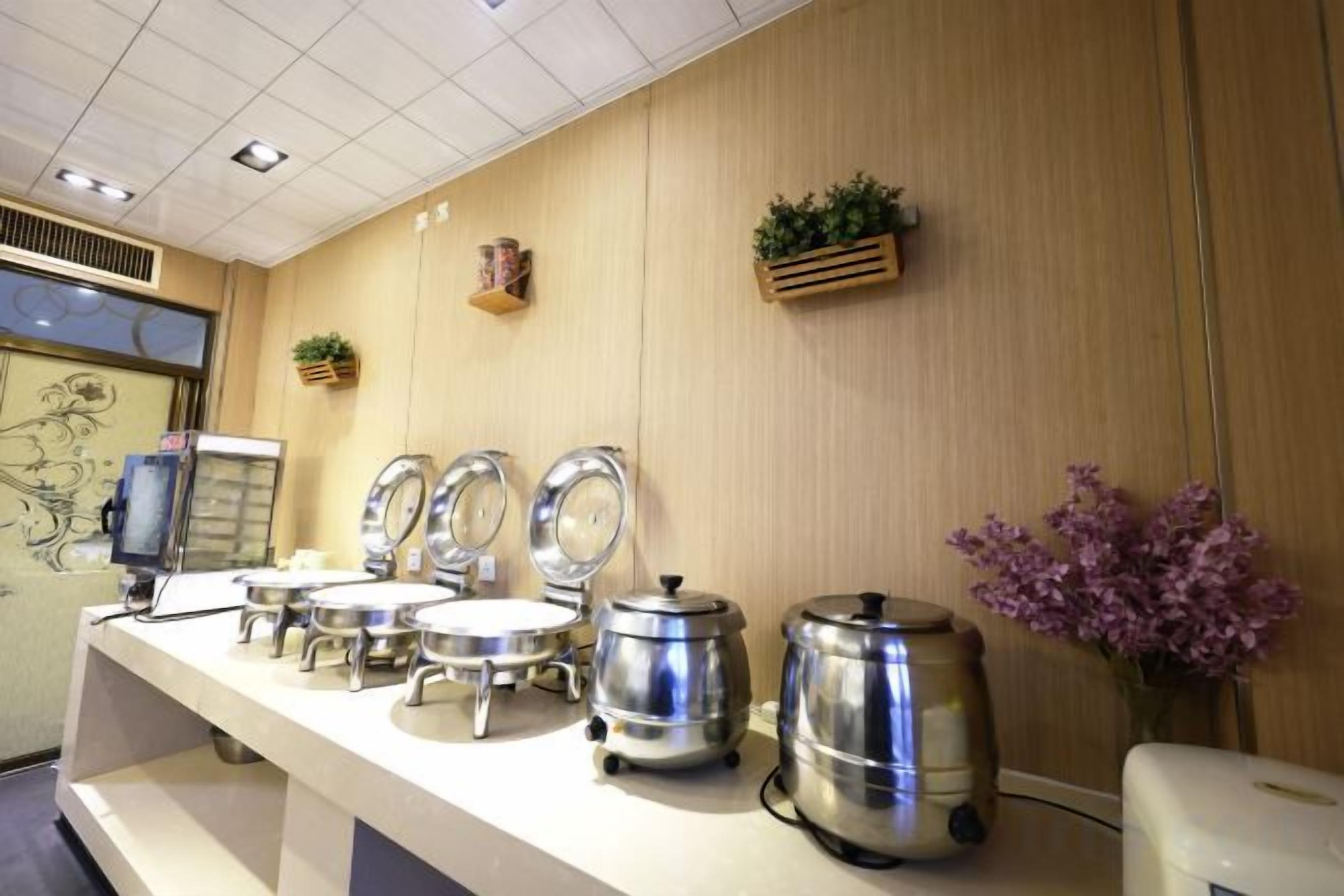 A buffet setup with multiple serving stations, a coffee machine, and decorative plants.