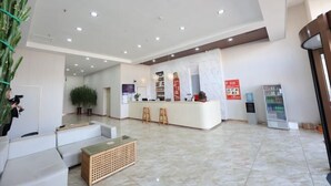 A modern lobby with a reception desk, seating area, and a vending machine. - Aoliyang Business Hotel (Zhuanghe Jinma Plaza) (Zhuanghe)
