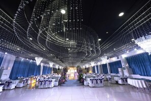 A banquet hall with rows of tables, a chandelier, and draped curtains. - Aoliyang Business Hotel (Zhuanghe Jinma Plaza) (Zhuanghe)