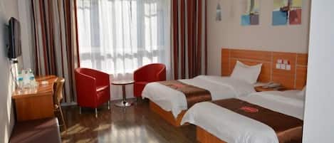 A hotel room with two beds, a desk, a chair, and a TV.