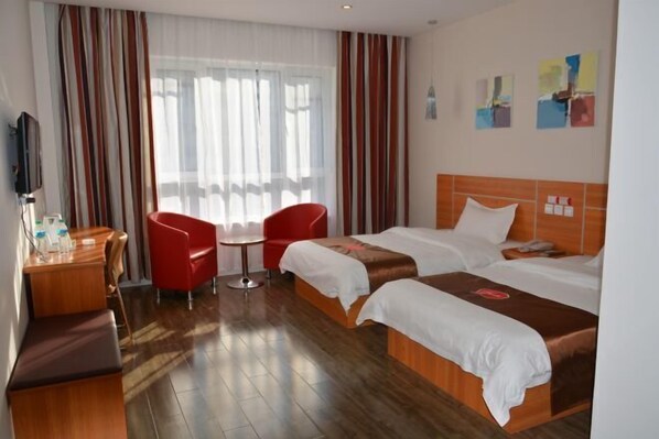 A hotel room with two beds, a desk, a chair, and a TV.