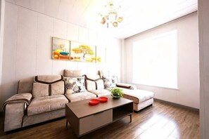 A modern living room with a sofa, a coffee table, and a painting on the wall. - Aoliyang Business Hotel (Zhuanghe Jinma Plaza) (Zhuanghe)