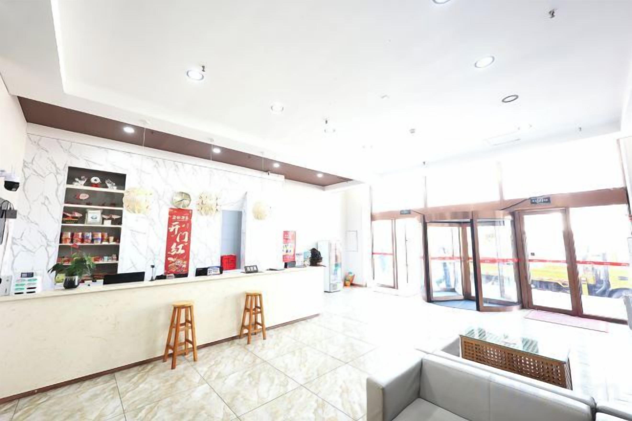 A hotel lobby with a reception desk, seating area, and large windows.