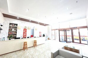 A hotel lobby with a reception desk, seating area, and large windows. - Aoliyang Business Hotel (Zhuanghe Jinma Plaza) (Zhuanghe)