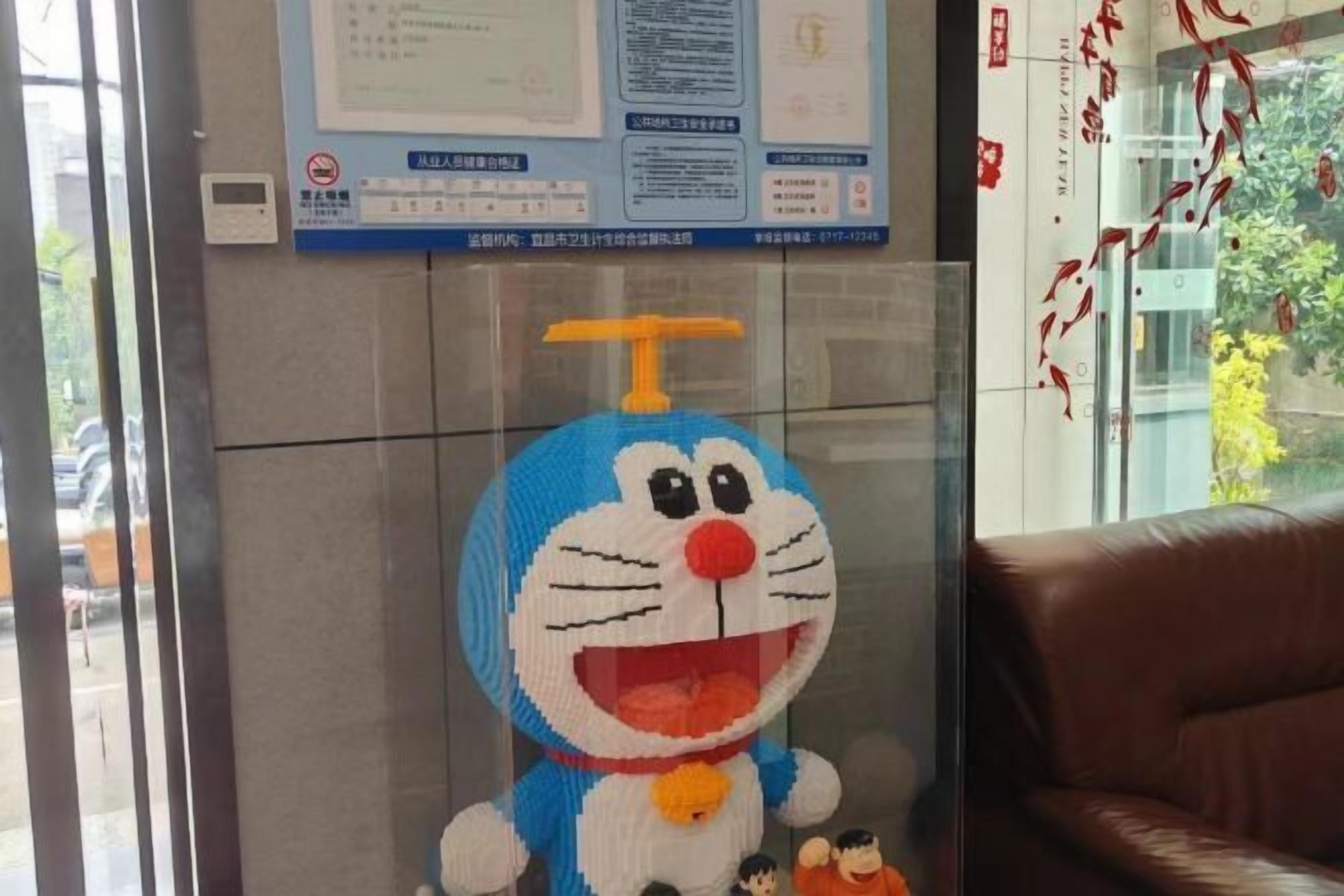 Un espace d’accueil agrémenté d’une grande sculpture représentant un chat aux couleurs bleu et blanc, d’un canapé en cuir marron et d’une cloison en verre.