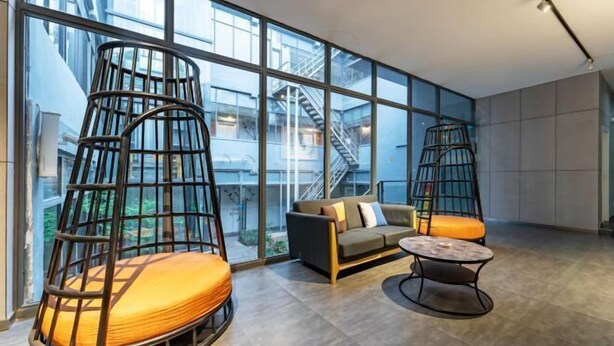 A modern interior with a sofa, two hanging chairs, and a small table. - Jinbo Hotel (Yichang)
