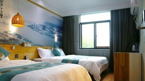 A hotel room with two beds, a large window with curtains, a wooden headboard, and a wall mural. - Jinbo Hotel (Yichang)