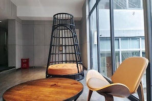 Un interior moderno con una mesa redonda de madera, una silla de metal negro con cojines y una silla sencilla con un cojín claro.