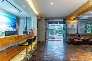 Een receptie met een houten balie, barstoelen, een televisie en een zithoek met leren banken.