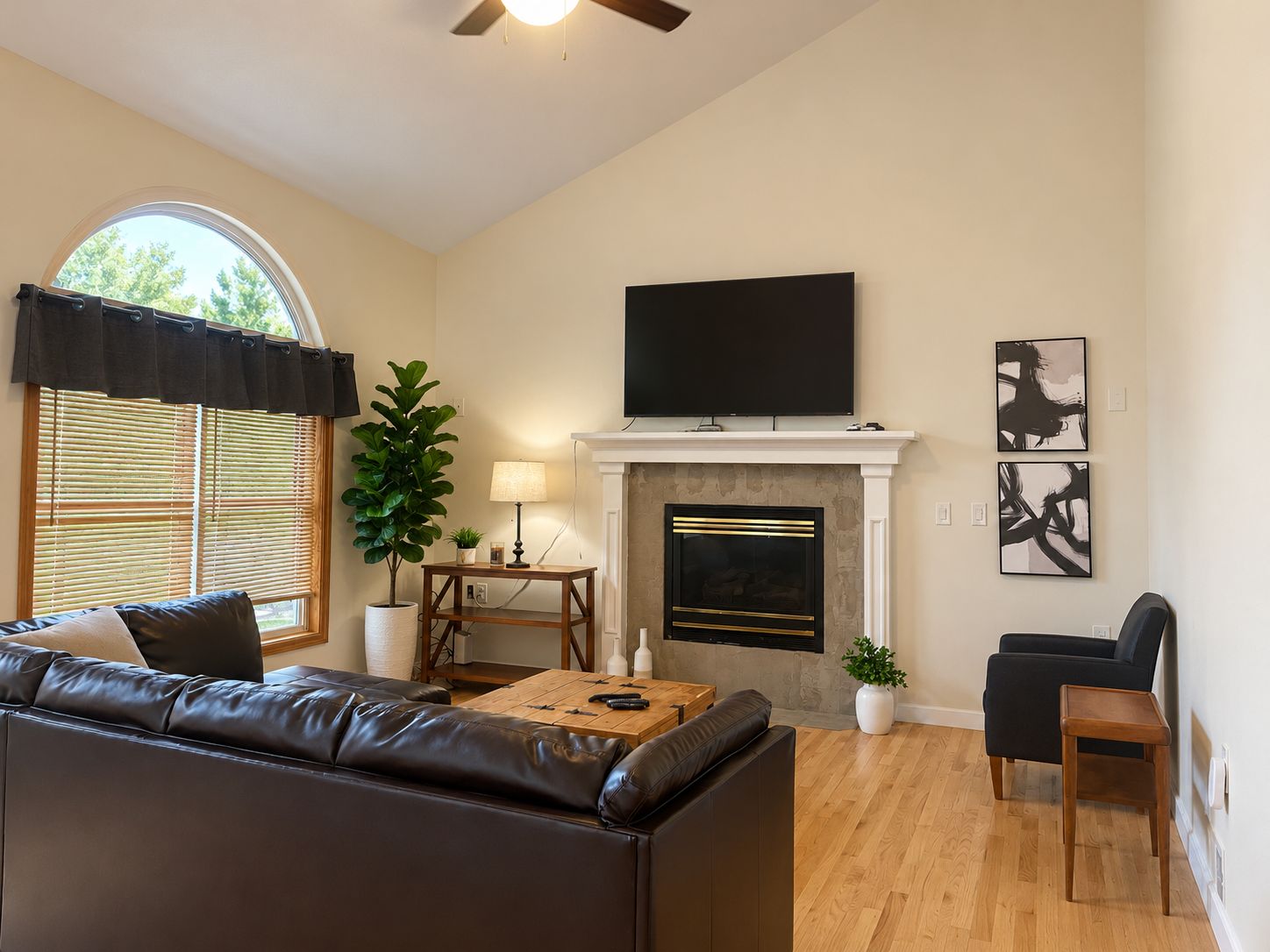A living room with a fireplace, a television mounted above it, a sofa, a coffee table, and a chair.