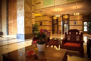 A lobby with a reception desk, seating area, and a large plant. - Golden Begonia Donggang Hotel Lincang (Lincang)