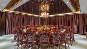 A formal dining room with a large round table, multiple chairs, and a chandelier. - Golden Begonia Donggang Hotel Lincang (Lincang)