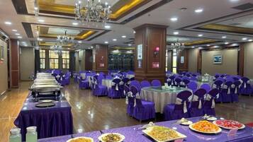 A banquet hall with round tables, purple tablecloths, and chairs.