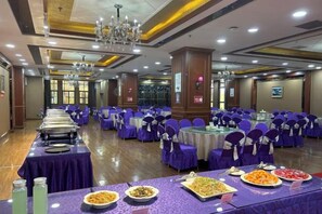 A banquet hall with round tables, purple tablecloths, and chairs.