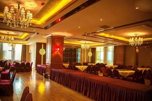 A banquet hall with long tables, chandeliers, and a high ceiling.