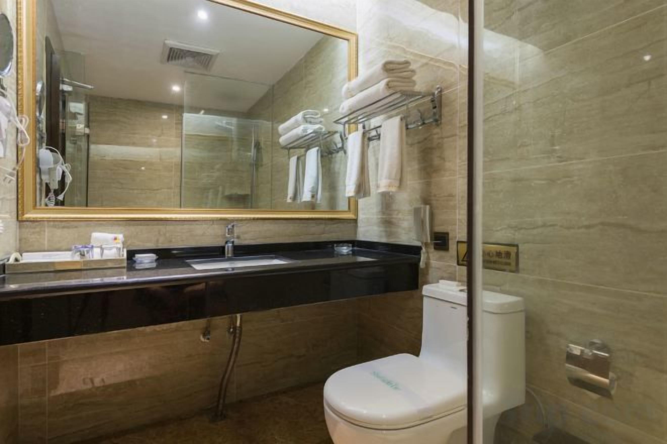A modern bathroom with a black countertop, a white toilet, and a glass-enclosed shower area.
