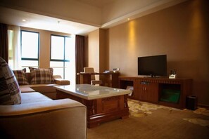A living room with a sofa, a coffee table, a TV, and a fireplace. - Golden Begonia Donggang Hotel Lincang (Lincang)