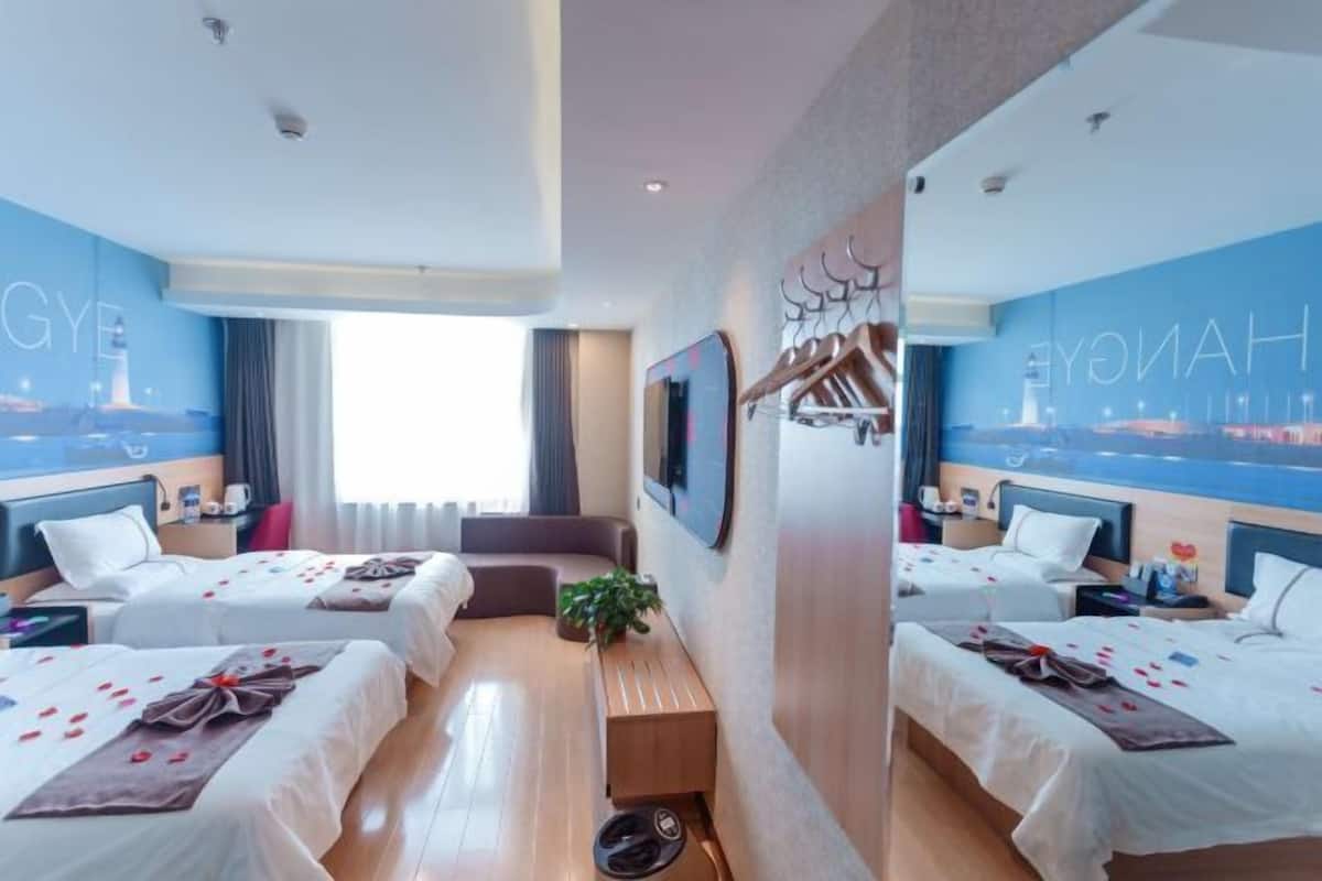Een hotelkamer met twee bedden, een bank, een televisie en uitzicht op de stad.