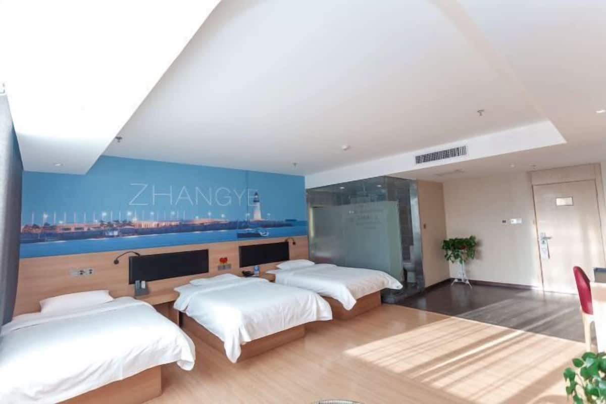 Hotelkamer met twee bedden, een stadsdoeken muurschildering, een massagestoel en een plant.