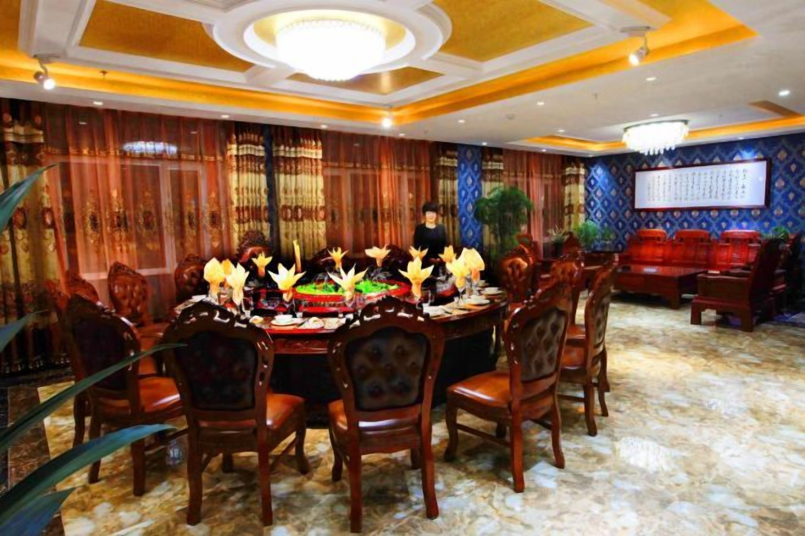 A formal dining room with a round table, chairs, and a chandelier.