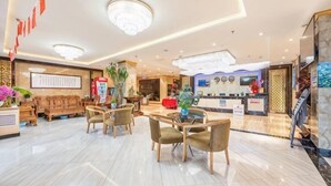 Eine Hotelhalle mit Empfangstresen, Sitzgelegenheiten und einer großen Kronleuchter.