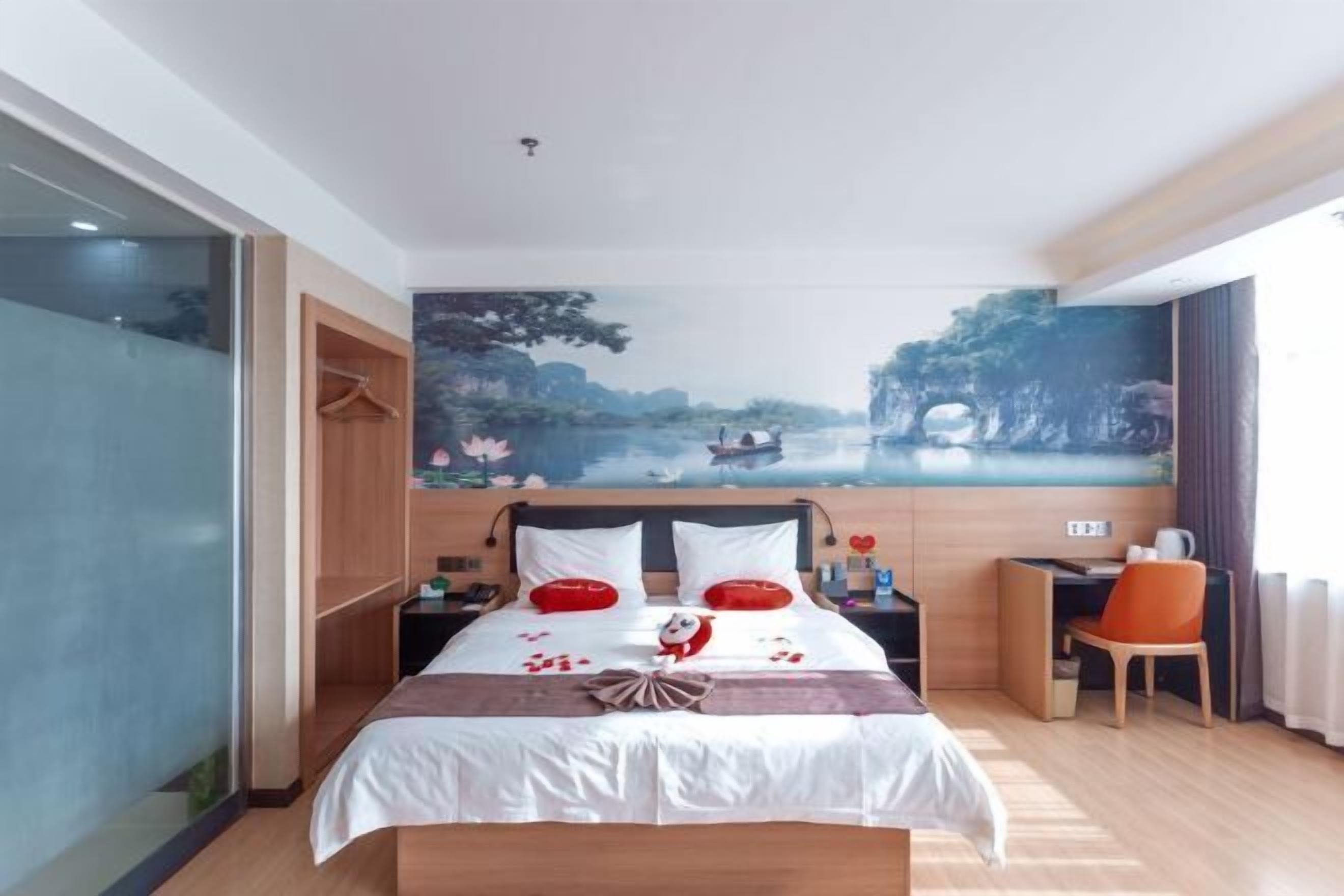 Ein Hotelzimmer mit einem Bett, einem Schreibtisch, einem Sessel und einem großen Wandbild.