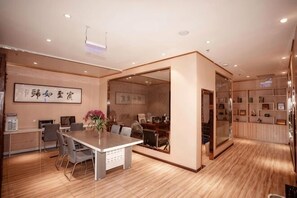 Une chambre d’hôtel avec un plancher en bois, une table à manger avec des chaises, un canapé, un téléviseur et un grand miroir.