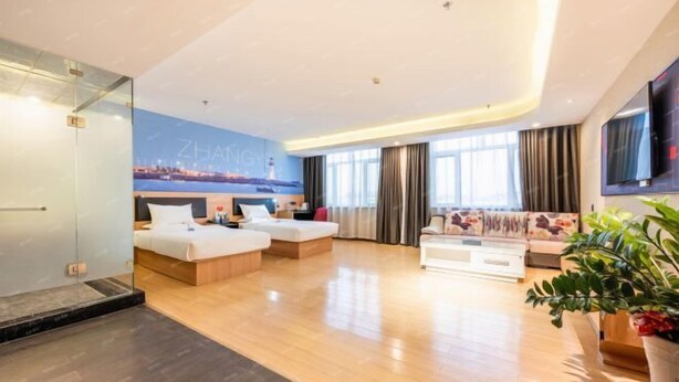 Ein modernes Hotelzimmer mit einem großen Bett, einer Couch, einem Couchtisch und einem Fernseher.