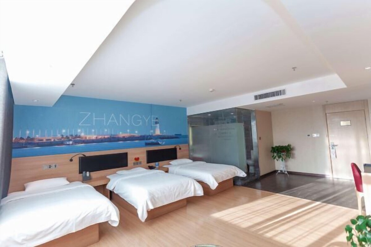 Ein Hotelzimmer mit zwei Betten, einem großen Fenster und einem Wandgemälde einer Stadtansicht.