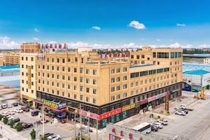 Un hotel de varios pisos con un patio central, varias tiendas en la planta baja y un estacionamiento.