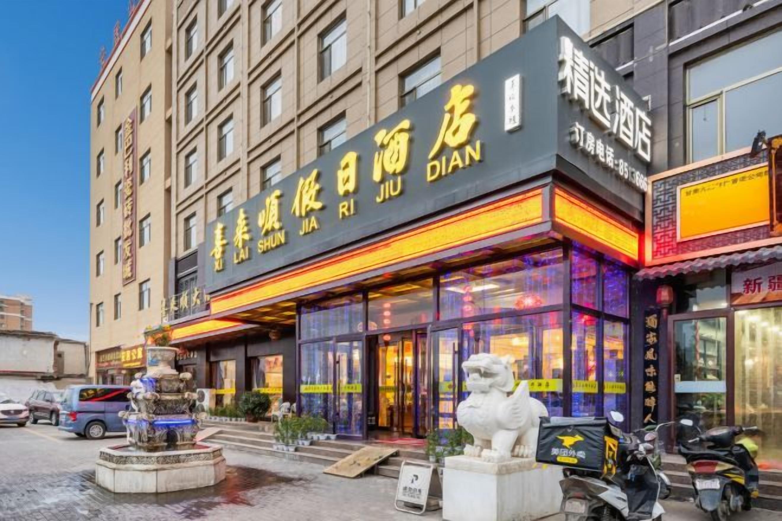 A hotel with a prominent sign, a fountain, and a statue in front.