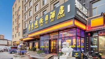 A hotel with a prominent sign, a fountain, and a statue in front.