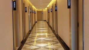 Ein Hotelgang mit einem geometrischen Fußbodenmuster, Zimmernummern an den Türen und einem modernen Design.