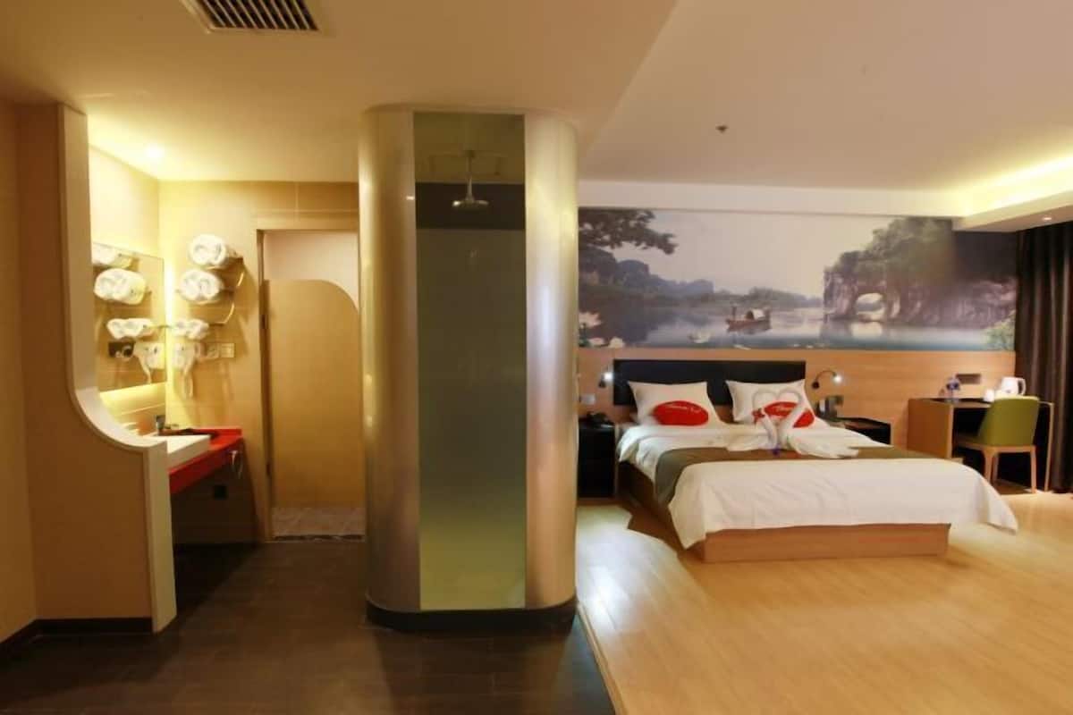 Een hotelkamer met een bed, een bureau, een stoel, een spiegel en een tv aan de muur.