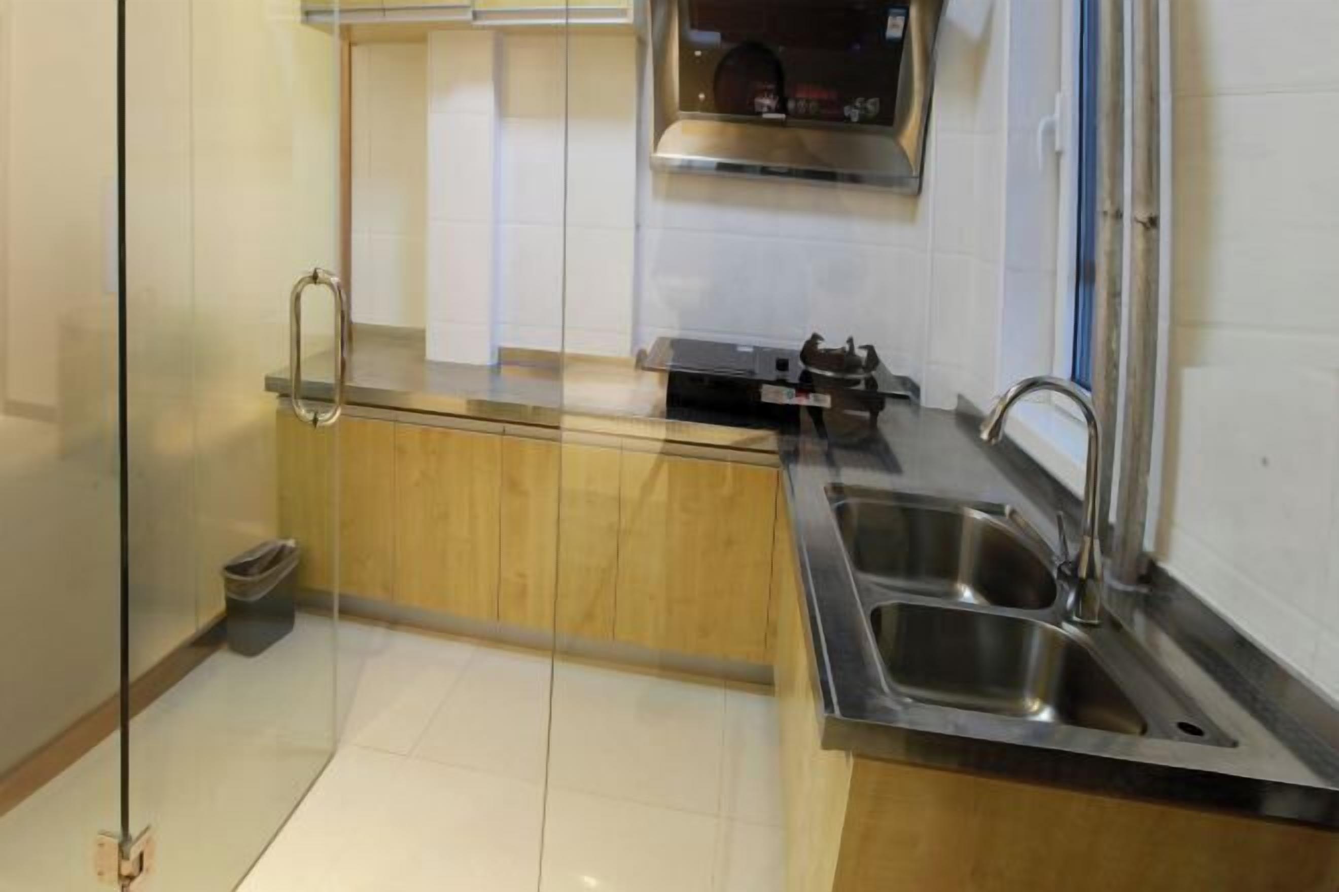 Een moderne keuken met houten kastjes, een roestvrijstalen spoelbak en een glazen scheidingswand.