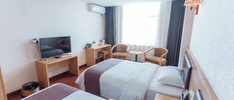 Ein Hotelzimmer mit zwei Betten, einem Schreibtisch, einem Stuhl, einem Fernseher und einem Fenster mit Vorhängen.