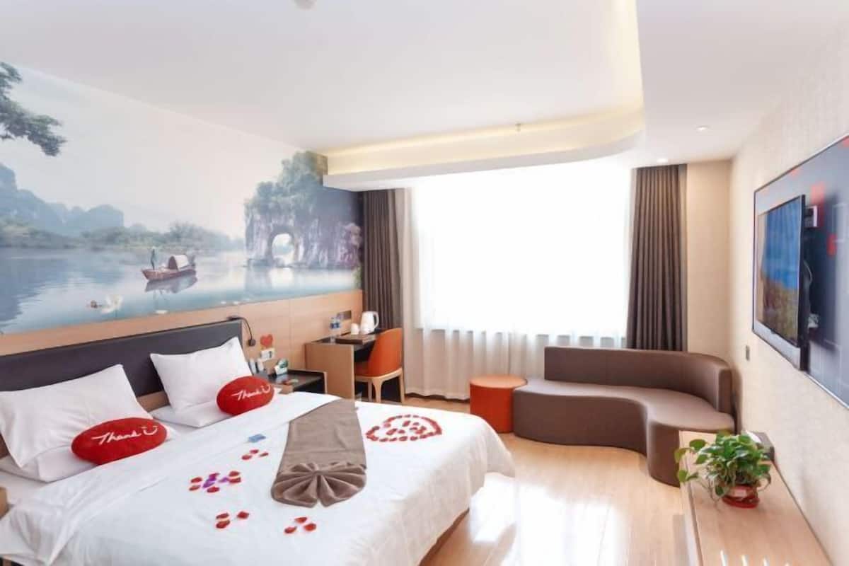 Een hotelkamer met een bed, een bureau, een bank en een groot raam.
