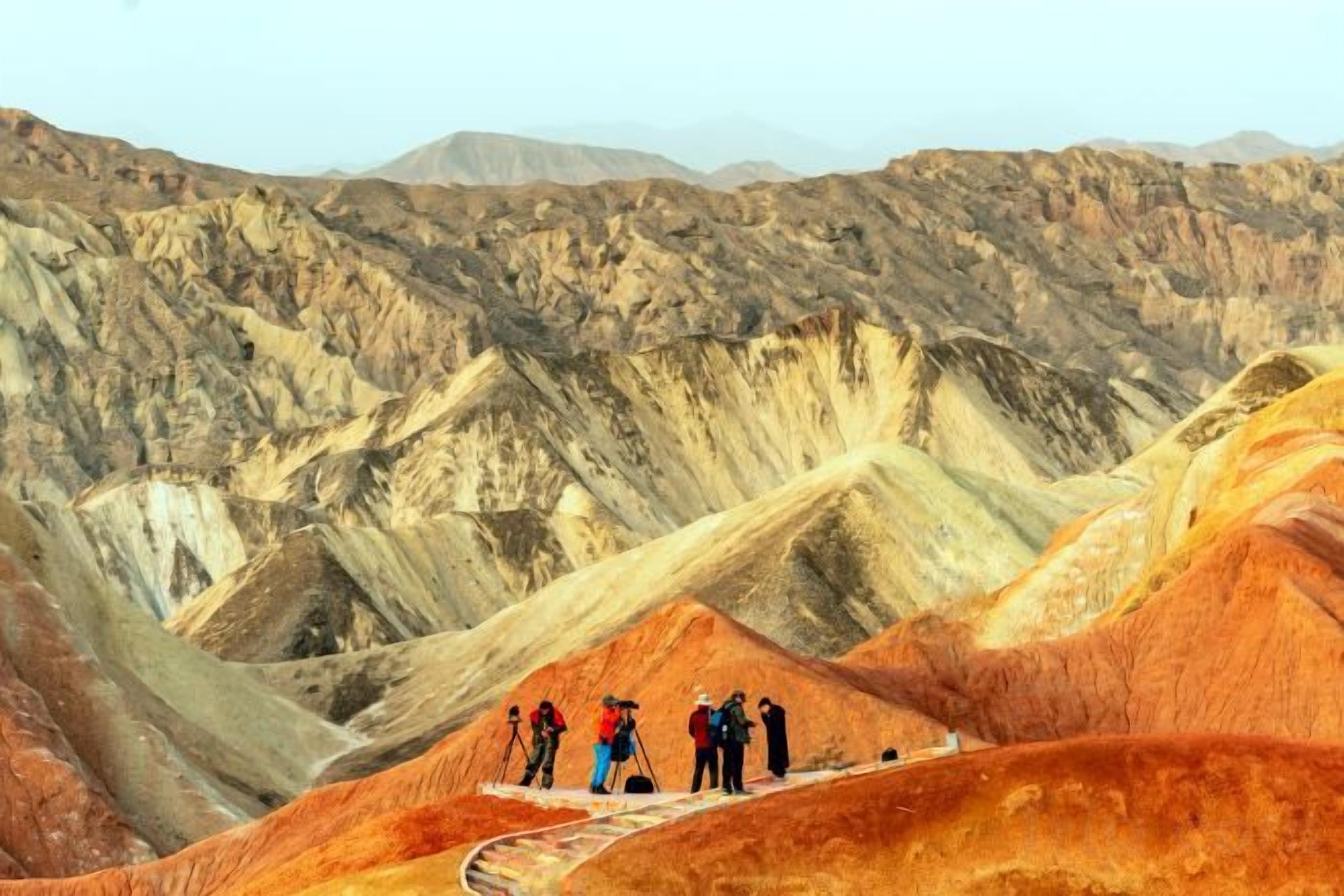 A group of people on a ridge overlooking a rugged, mountainous landscape.