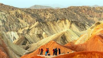 A group of people on a ridge overlooking a rugged, mountainous landscape.
