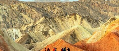 A group of people on a ridge overlooking a rugged, mountainous landscape.
