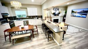 Une cuisine moderne avec un coin repas, un plancher en bois et un grand îlot central doté de tabourets de bar.