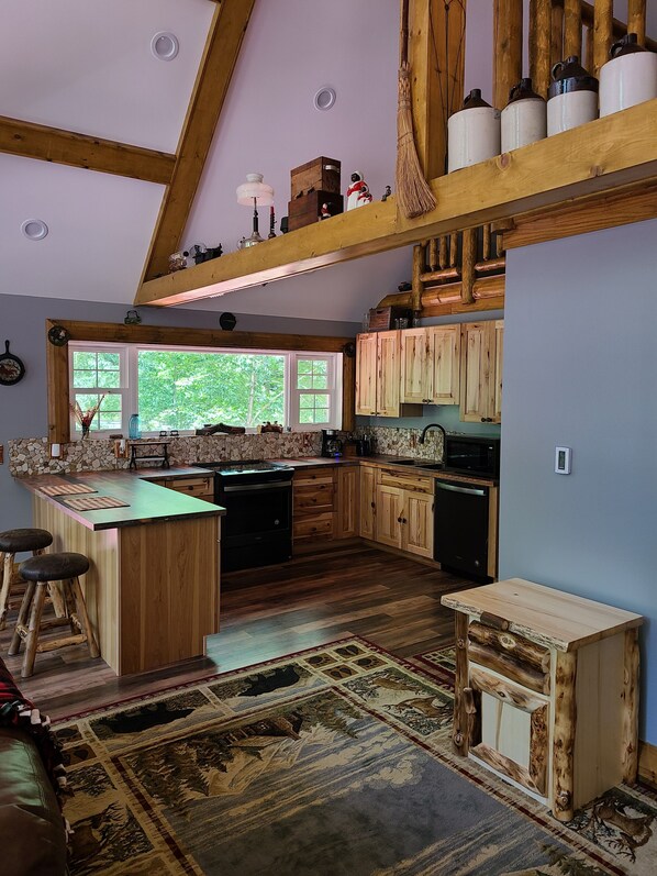 Una cocina rústica con vigas de madera, una isla grande y vistas al verdor exterior.