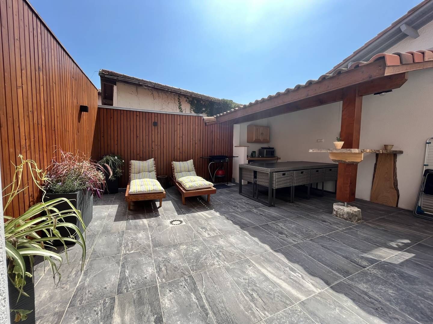 A patio area with two wooden chairs, a table, and a pergola structure.