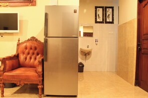 Une petite cuisine équipée d’un réfrigérateur, d’un évier et d’une chaise.