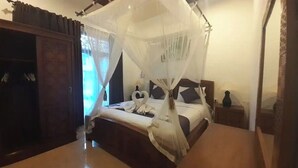 Ein Schlafzimmer mit einem Himmelbett, einem Holzschrank und einem Nachttisch mit Lampe.