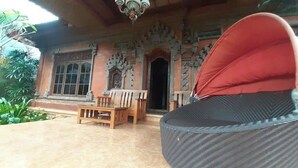 Ein traditionelles Gebäude mit aufwendiger Architektur, einer gefliesten Terrasse und einer hölzernen Bank.