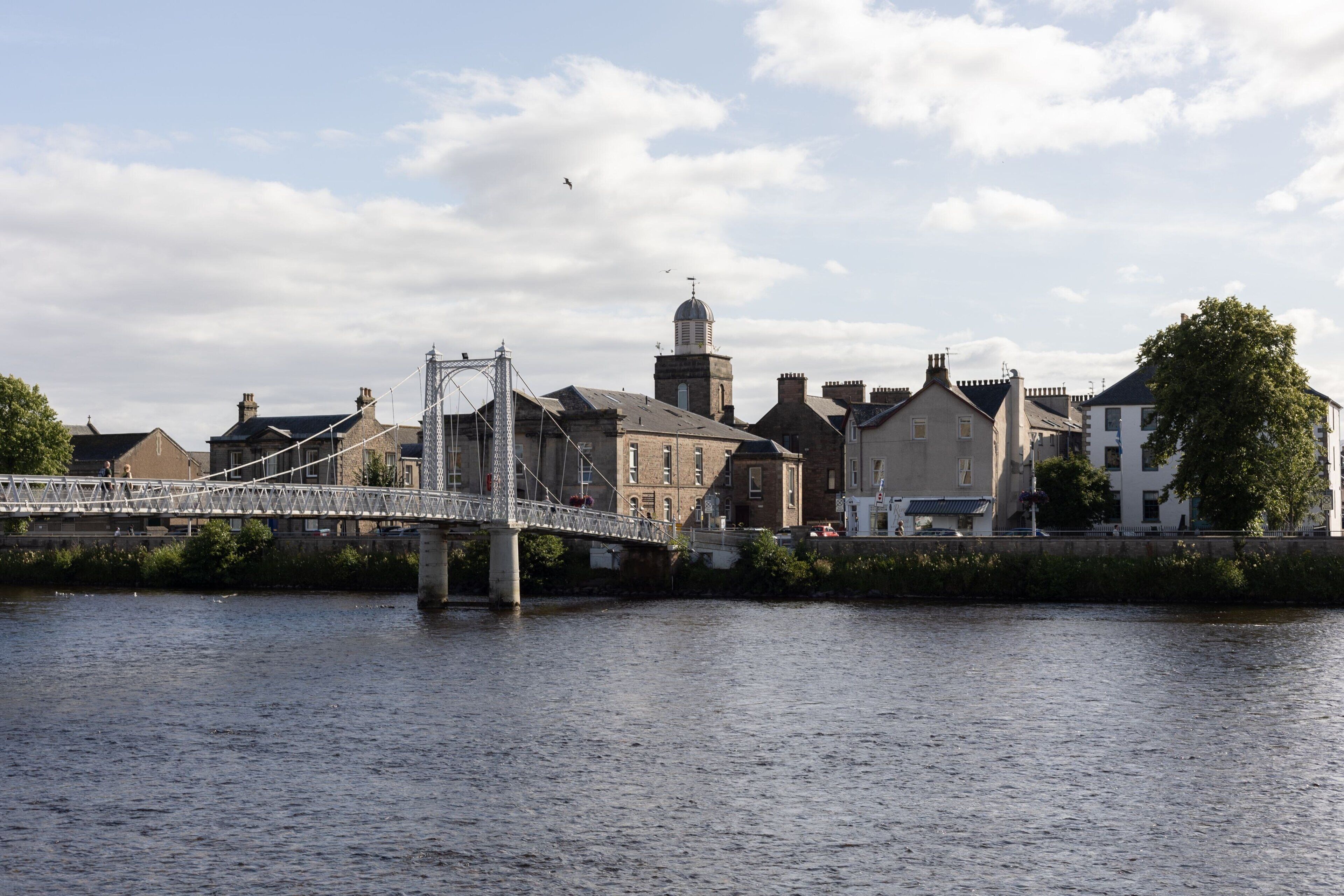 A bridge over a river with buildings in the background.