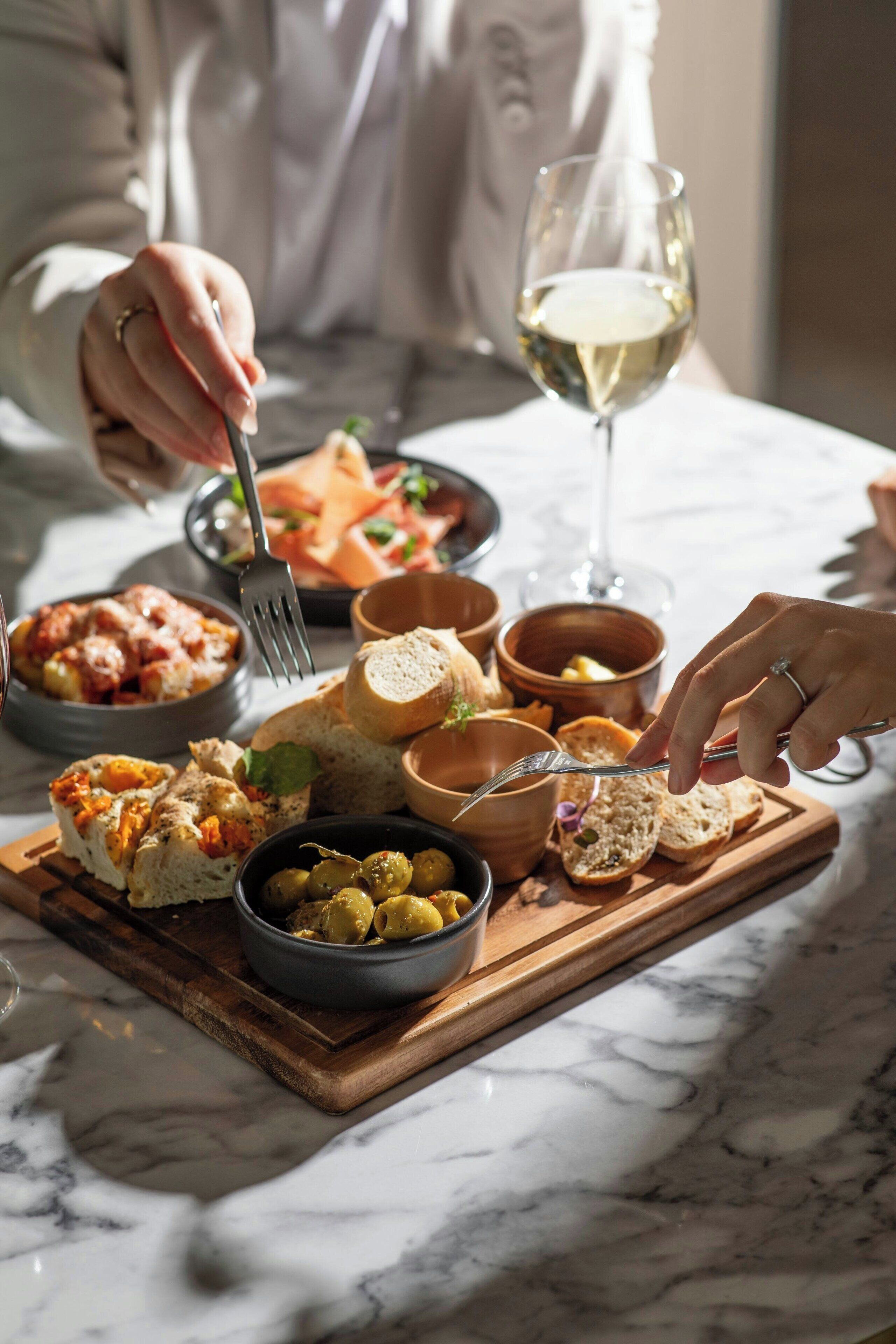 A dining table with various dishes and a glass of white wine.